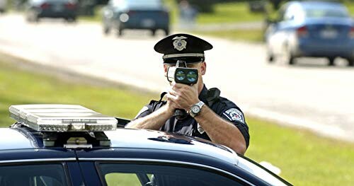 Police officer using a radar gun on the road.